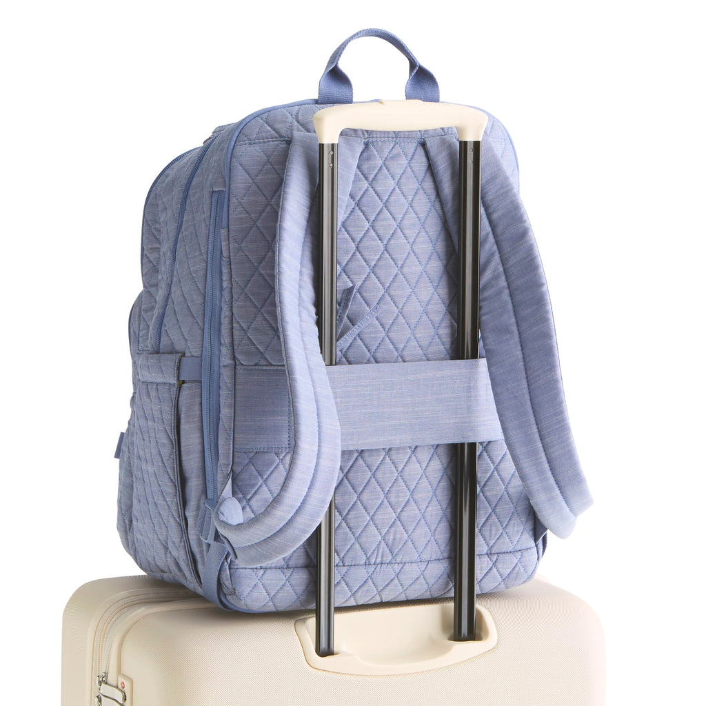 Blue quilted backpack on a suitcase with a white background