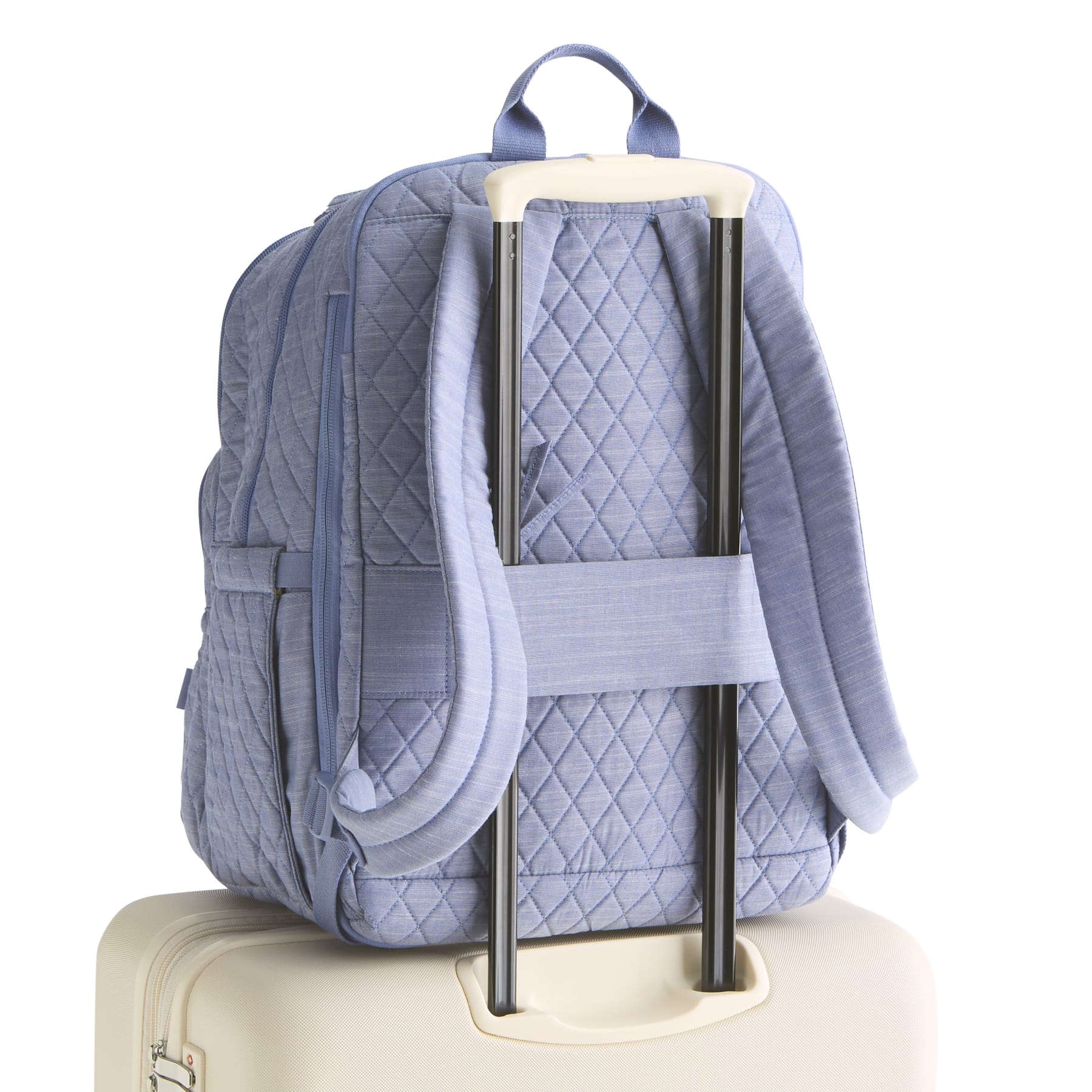 Blue quilted backpack on a suitcase with a white background