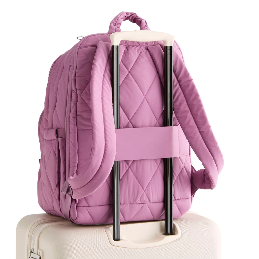 Purple quilted backpack attached to a suitcase on a white background