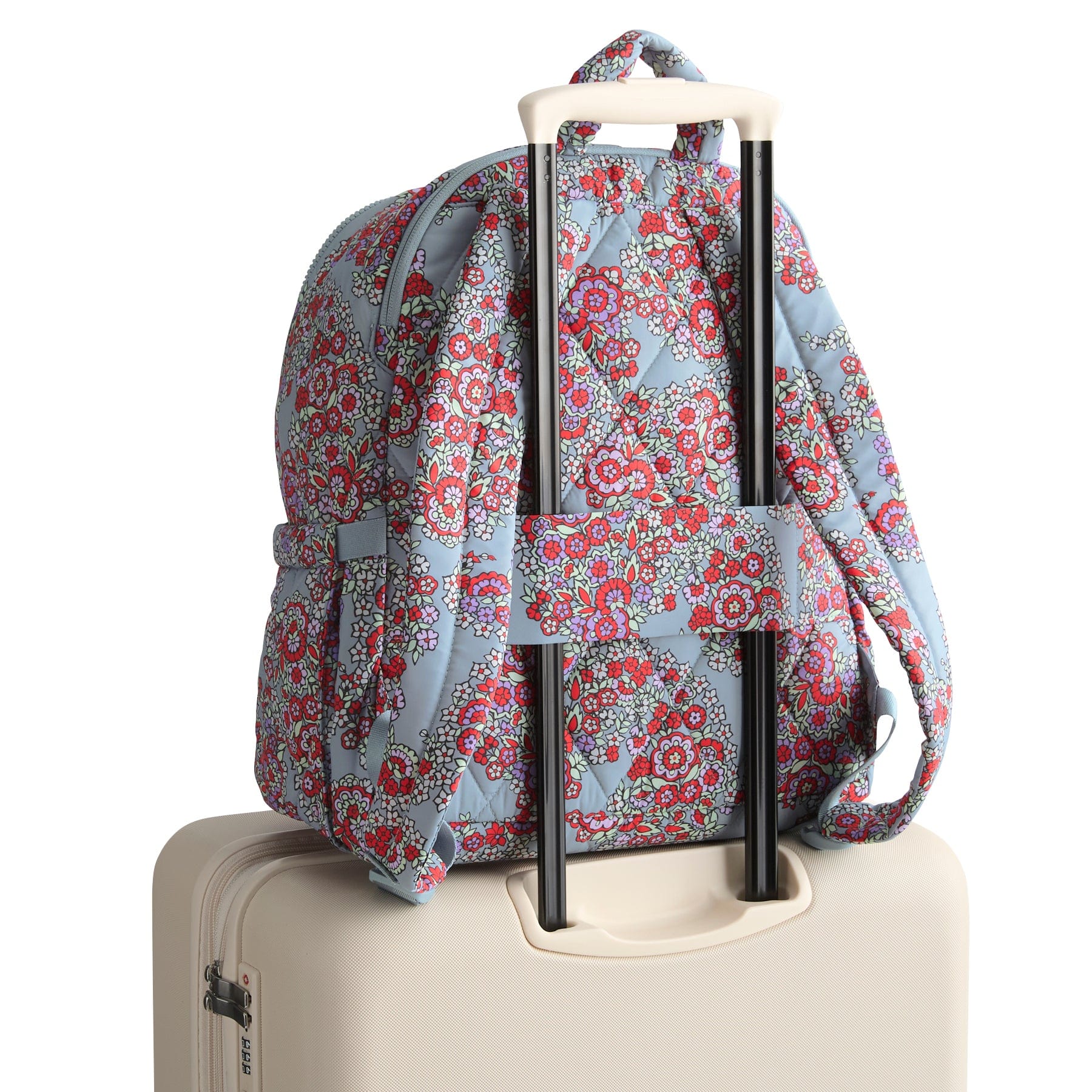 Floral-patterned backpack on top of a suitcase with a white background