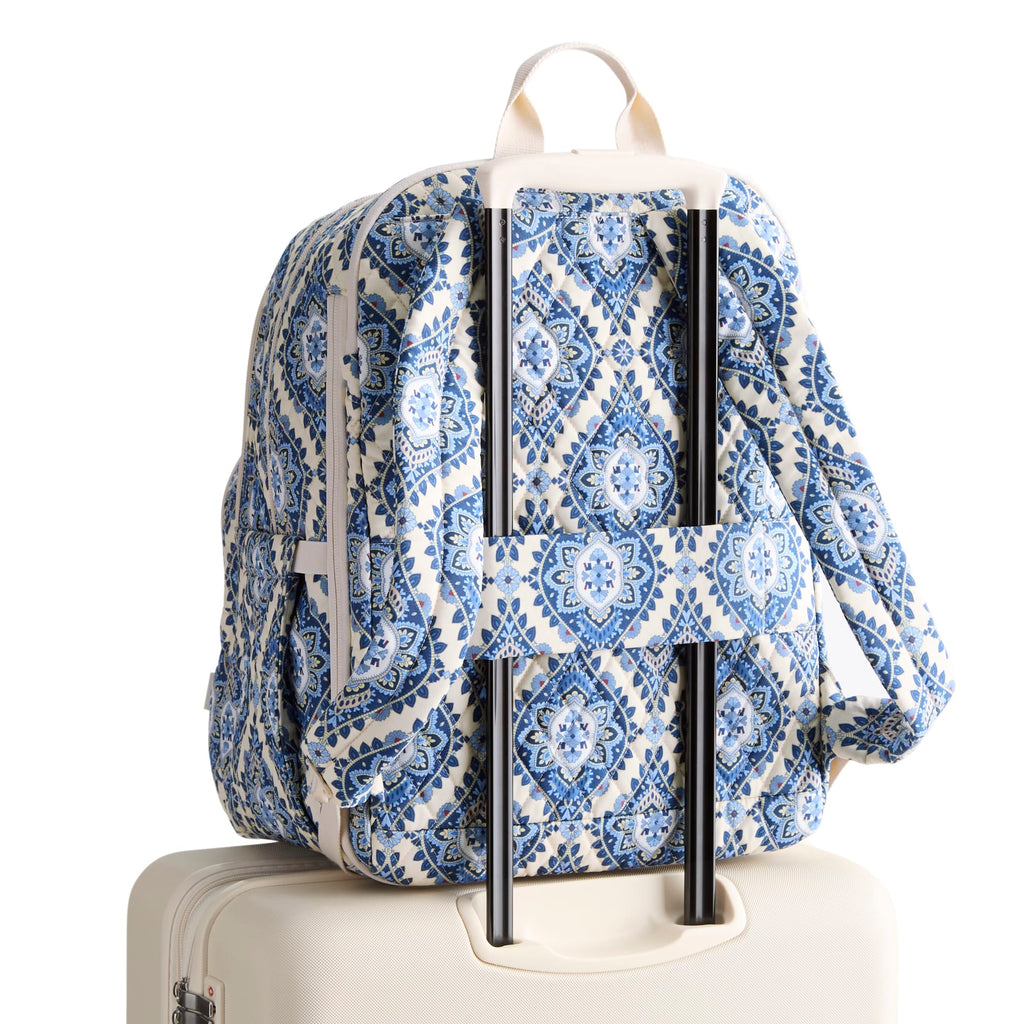 Blue and white patterned backpack on a suitcase with a white background