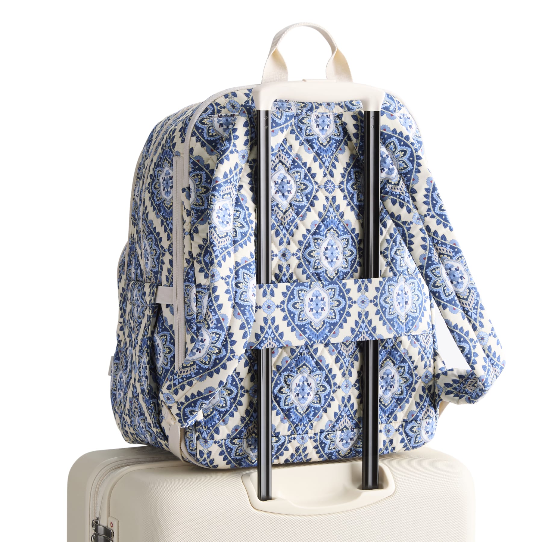 Blue and white patterned backpack on a suitcase with a white background
